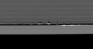 Moons in the rings create vertical waves due to gravitational forces.